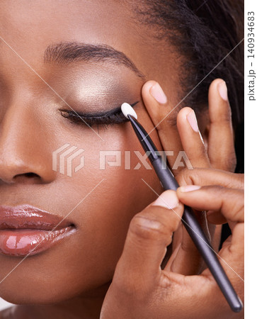 Closeup of black woman, brush and eyeshadow with makeup, beauty and lashes with eyeliner. Skin glow, hands and cosmetic product application with tools for cosmetology, shimmer or glitter with shine Closeup of black woman, brush and eyeshadow with makeup, beauty and lashes with eyeliner. Skin glow, hands and cosmetic product application with tools for cosmetology, shimmer or glitter with shine 140934683
