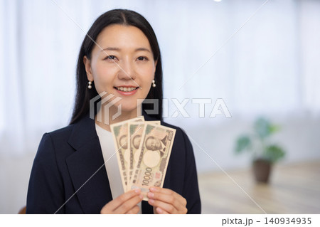 一万円札を3枚持ちカメラ目線で微笑む若い日本人のビジネスウーマン 140934935