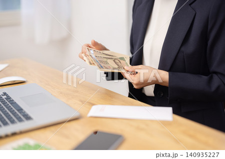 一万円札を広げて数を数える女性の手元のクローズアップ 140935227
