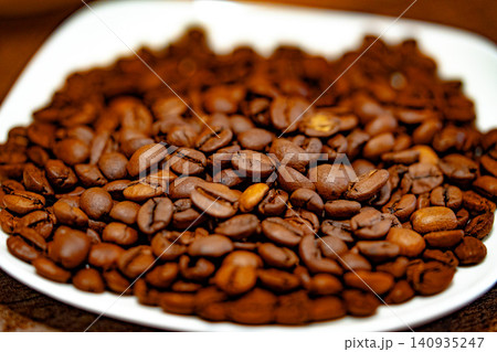 Coffee beans on a white plate. dark background Coffee beans on a white plate. dark background 140935247