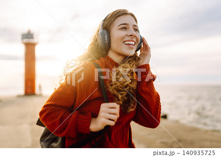 Relaxed woman enjoying music by the waterfront while wearing headphone. Travel and blogging concept 140935725