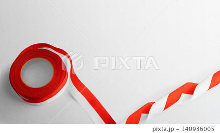 A roll of red and white warning hazard tape unrolling on a plain white surface with space for text. Hari Kemerdekaan, Merdeka, and Dirgahayu Indonesia on 17 Agustus A roll of red and white warning hazard tape unrolling on a plain white surface with space for text. Hari Kemerdekaan, Merdeka, and Dirgahayu Indonesia on 17 Agustus 140936005