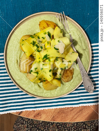 Baked potatoes are topped with slices of fermented zucchini and served alongside a green pea sauce with broccoli. This meal is prepared for a healthy breakfast Baked potatoes are topped with slices of fermented zucchini and served alongside a green pea sauce with broccoli. This meal is prepared for a healthy breakfast 140936071