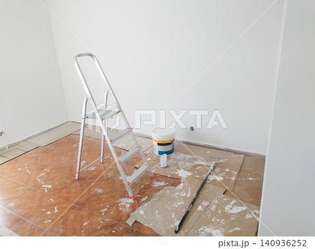An empty room during a home renovation, featuring a stepladder, a paint bucket, and a roller on cardboardcovered floors. Ideal for DIY, remodeling, and interior design concepts. An empty room during a home renovation, featuring a stepladder, a paint bucket, and a roller on cardboardcovered floors. Ideal for DIY, remodeling, and interior design concepts. 140936252