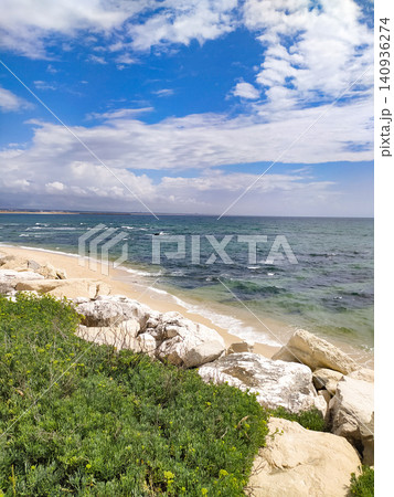 A serene coastal landscape with white rocks, lush green plants, golden sand, and a turquoise ocean under a bright, cloudy blue sky. Inspires feelings of peace and calm. Nobody. A serene coastal landscape with white rocks, lush green plants, golden sand, and a turquoise ocean under a bright, cloudy blue sky. Inspires feelings of peace and calm. Nobody. 140936274
