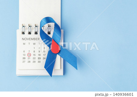 Blue ribbon with a red blood drop on a calendar over a blue background with copy space, World Diabetes Day on November 14 concept 140936601