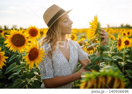 Woman strolling through field with sunflowers. Fashion, lifestyle, travel and vacations concept. 140936696