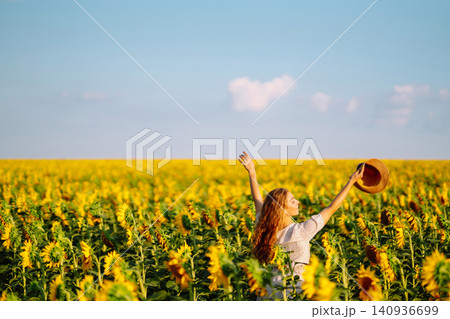 Woman strolling through field with sunflowers. Fashion, lifestyle, travel and vacations concept. Woman strolling through field with sunflowers. Fashion, lifestyle, travel and vacations concept. 140936699