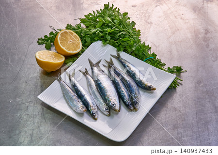 Seven sardines on a white plate with parsley and lemon Seven sardines on a white plate with parsley and lemon 140937433