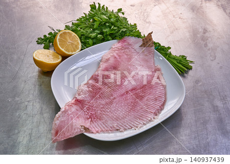 Slice of skate on a white plate with parsley and lemon Slice of skate on a white plate with parsley and lemon 140937439