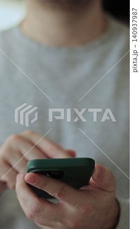 Vertical video Close-up young man using smartphone in living room at home. Chatting on social networks online. Vertical video Close-up young man using smartphone in living room at home. Chatting on social networks online. 140937987