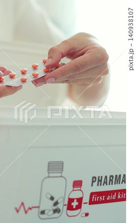 Vertical video Woman takes out blister of pills from first aid kit at home. Vertical video Woman takes out blister of pills from first aid kit at home. 140938107