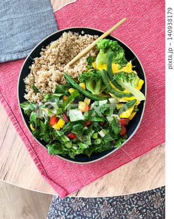 Quinoa bowl features boiled eggs, green beans, and broccoli. A fresh salad sits nearby. A cup of coffee completes the healthy breakfast setting Quinoa bowl features boiled eggs, green beans, and broccoli. A fresh salad sits nearby. A cup of coffee completes the healthy breakfast setting 140938179