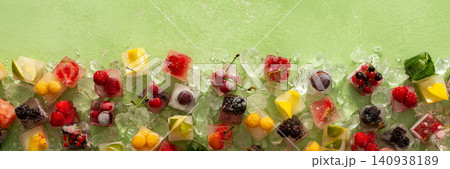 Green background with ice cubes with frozen berries and fruits and mint, banner Green background with ice cubes with frozen berries and fruits and mint, banner 140938189