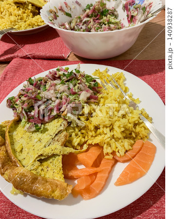 A plate holds rice cooked with turmeric, an omelette, fresh salad, and slices of red fish, prepared for a nourishing meal at home during the morning or afternoon A plate holds rice cooked with turmeric, an omelette, fresh salad, and slices of red fish, prepared for a nourishing meal at home during the morning or afternoon 140938287