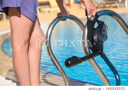 A diving mask in a woman's hand against the background of water 140938353
