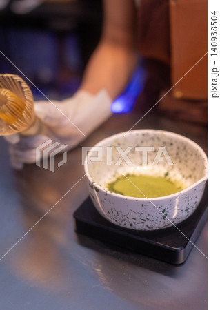 Close-up of a barista preparing a fresh matcha green tea latte in a cafe 140938504
