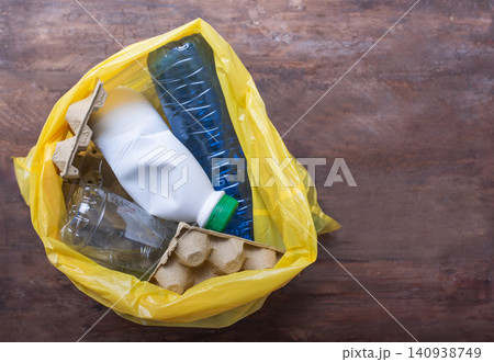 Yellow plastic bag filled with recyclable waste including plastic bottles, milk carton, and egg carton, emphasizing the importance of recycling and environmental sustainability Yellow plastic bag filled with recyclable waste including plastic bottles, milk carton, and egg carton, emphasizing the importance of recycling and environmental sustainability 140938749