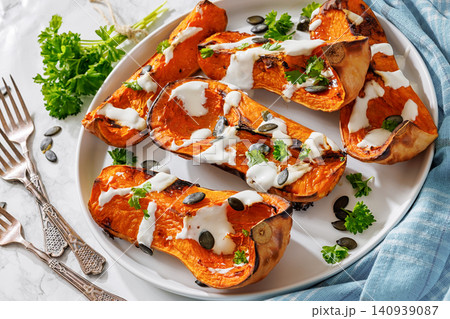 Baked butternut squash halves with yogurt sauce 140939087