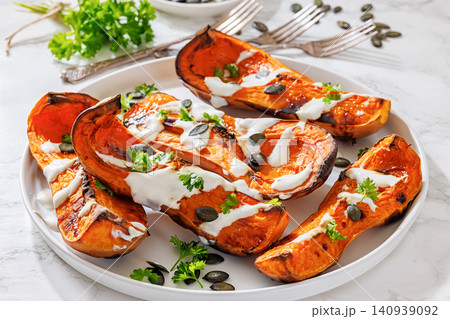 Baked butternut squash halves with yogurt sauce 140939092