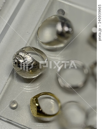 Jewelry rings displayed on a transparent tray, showcasing metallic design variety Jewelry rings displayed on a transparent tray, showcasing metallic design variety 140939665