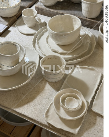 Handmade ceramic tableware set on wooden table showcasing artisanal craftsmanship Handmade ceramic tableware set on wooden table showcasing artisanal craftsmanship 140939666