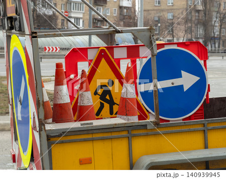 Road construction equipment with traffic cones and warning signs on a trailer, signaling safety and diversion to drivers for a secure urban infrastructure project on a city street Road construction equipment with traffic cones and warning signs on a trailer, signaling safety and diversion to drivers for a secure urban infrastructure project on a city street 140939945