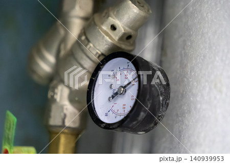 Industrial pressure gauge attached to metallic pipes shows system status in a heating unit, providing monitoring and diagnostic data for building maintenance and engineering operations Industrial pressure gauge attached to metallic pipes shows system status in a heating unit, providing monitoring and diagnostic data for building maintenance and engineering operations 140939953