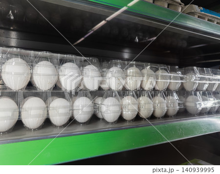Rows of fresh white chicken eggs in clear plastic containers arranged on a supermarket display shelf, highlighting retail grocery shopping and nutritious protein for a healthy diet Rows of fresh white chicken eggs in clear plastic containers arranged on a supermarket display shelf, highlighting retail grocery shopping and nutritious protein for a healthy diet 140939995