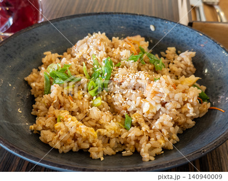 Fresh fried rice with scallions and sesame seeds served in a dark ceramic bowl, capturing authentic Asian culinary traditions for a delicious restaurant lunch or savory home dinner Fresh fried rice with scallions and sesame seeds served in a dark ceramic bowl, capturing authentic Asian culinary traditions for a delicious restaurant lunch or savory home dinner 140940009