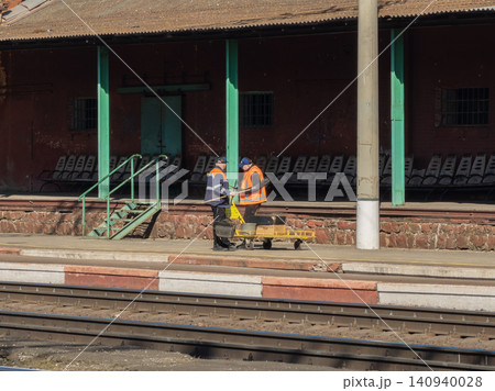 Railway workers in high visibility vests cleaning the platform at a train station, maintaining public infrastructure and ensuring safe transport environments for local daily commuters Railway workers in high visibility vests cleaning the platform at a train station, maintaining public infrastructure and ensuring safe transport environments for local daily commuters 140940028