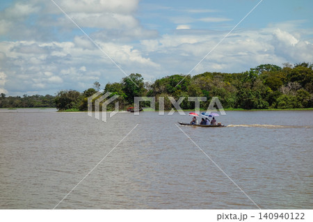 Locals navigating in canoe, shielding from sun with parasols. Brazilian Amazon rainforest river Locals navigating in canoe, shielding from sun with parasols. Brazilian Amazon rainforest river 140940122