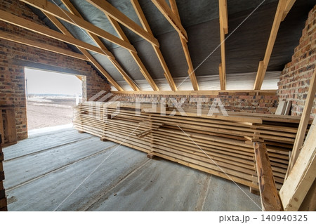 Interior of unfinished brick house with concrete floor, bare walls ready for plastering and wooden roofing frame attic under construction. 140940325
