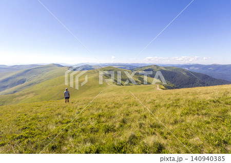 Lonely hiker standing in mountains. Tourist man enjoy mountain view Lonely hiker standing in mountains. Tourist man enjoy mountain view 140940385