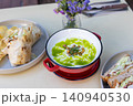 Close-up of a warm bowl of creamy broccoli soup garnished with fresh cream 140940530