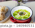 Close-up of a warm bowl of creamy broccoli soup garnished with fresh cream 140940531