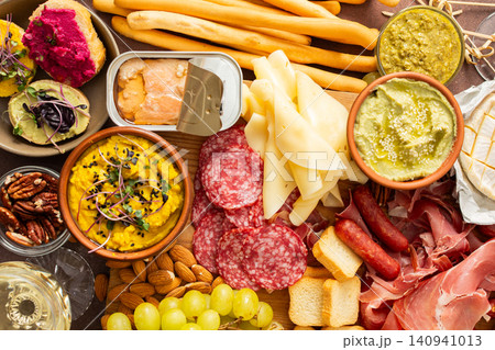 This festive spread features an array of cheese, cured meats, hummus, nuts, and fresh vegetables. Perfect for sharing at a casual get-together or celebration with friends This festive spread features an array of cheese, cured meats, hummus, nuts, and fresh vegetables. Perfect for sharing at a casual get-together or celebration with friends 140941013