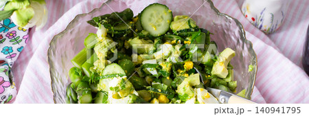 A bowl filled with cucumber salad features boiled eggs, asparagus, and avocado mixed with fresh greens. The salad is made from organic vegetables harvested in summer, banner A bowl filled with cucumber salad features boiled eggs, asparagus, and avocado mixed with fresh greens. The salad is made from organic vegetables harvested in summer, banner 140941795