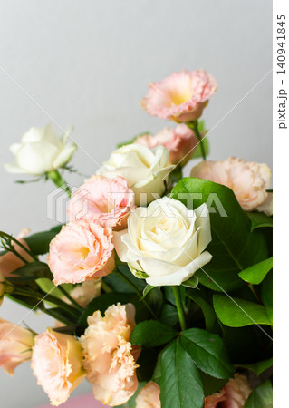 Fresh roses and eustomas are arranged in a bouquet with green leaves. The setting has a plain background and bright lighting. This moment captures floral beauty Fresh roses and eustomas are arranged in a bouquet with green leaves. The setting has a plain background and bright lighting. This moment captures floral beauty 140941845