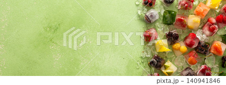 Green background with ice cubes with frozen berries and fruits and mint, banner Green background with ice cubes with frozen berries and fruits and mint, banner 140941846