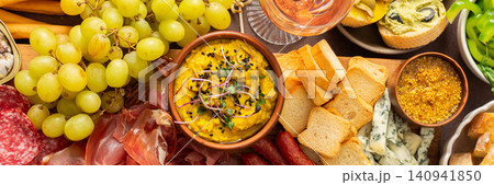 Taste a variety of flavors with this charcuterie board filled with cheese, sausages, hummus, nuts, and fresh sandwiches, perfect for any gathering, banner Taste a variety of flavors with this charcuterie board filled with cheese, sausages, hummus, nuts, and fresh sandwiches, perfect for any gathering, banner 140941850