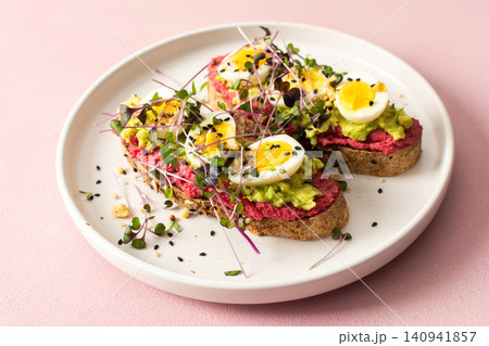 Fresh sandwiches made with gluten free bread topped with beetroot hummus, pesto, boiled quail eggs, and microgreens served on a simple plate Fresh sandwiches made with gluten free bread topped with beetroot hummus, pesto, boiled quail eggs, and microgreens served on a simple plate 140941857