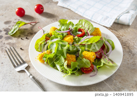 Summer fresh vegetable salad with crispy breaded feta cheese on a textured stonesurface. Tasty appetizer ready to eat. 140941895