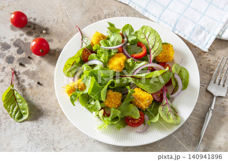 Summer fresh vegetable salad with crispy breaded feta cheese on a textured stonesurface. Tasty appetizer ready to eat. 140941896