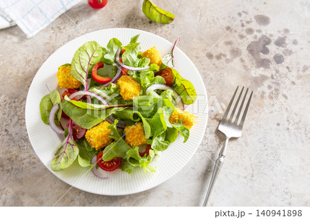 Summer fresh vegetable salad with crispy breaded feta cheese on a textured stonesurface. Tasty appetizer ready to eat. Copy space. 140941898