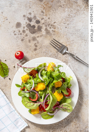 Summer fresh vegetable salad with crispy breaded feta cheese on a textured stonesurface. Tasty appetizer ready to eat. Top view flat lay background. Copy space. Summer fresh vegetable salad with crispy breaded feta cheese on a textured stonesurface. Tasty appetizer ready to eat. Top view flat lay background. Copy space. 140941901