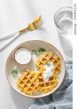 Vegetarian potato waffles with natural yogurt and dill on a plate on a light background Vegetarian potato waffles with natural yogurt and dill on a plate on a light background 140942133