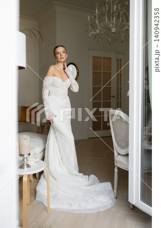 Bride in elegant white wedding dress posing indoors Bride in elegant white wedding dress posing indoors 140942358