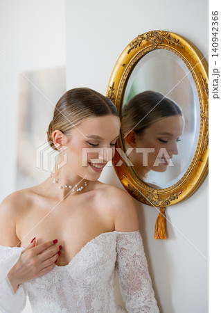 Elegant bride looking at reflection in ornate mirror 140942366