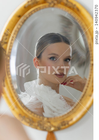Woman reflecting on beauty and elegance in mirror Woman reflecting on beauty and elegance in mirror 140942370